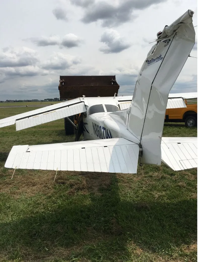 The Cessna 172 nosed over on the grass beside the runway, with the bent vertical stabilizer and empennage visible