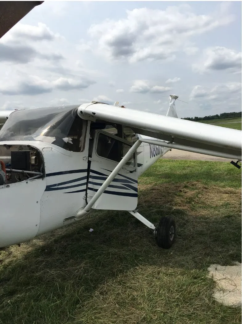 Close view of the damaged left wing, lift strut, and cockpit area after the accident