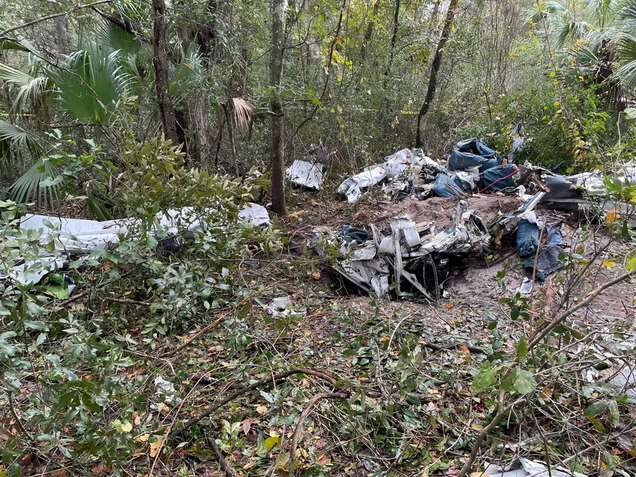 Overview of the wreckage in heavily wooded terrain at the accident site