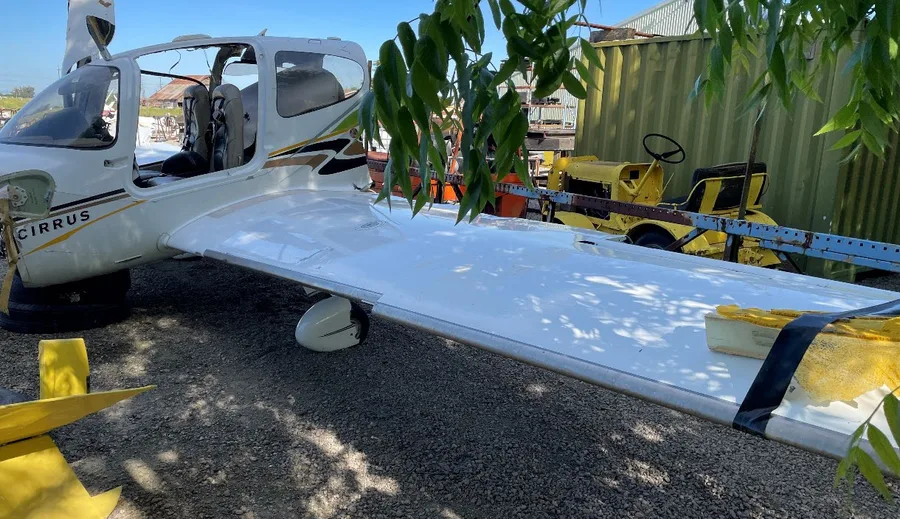 The recovered Cirrus SR22 airframe at the examination yard, showing the open doors and overall accident damage